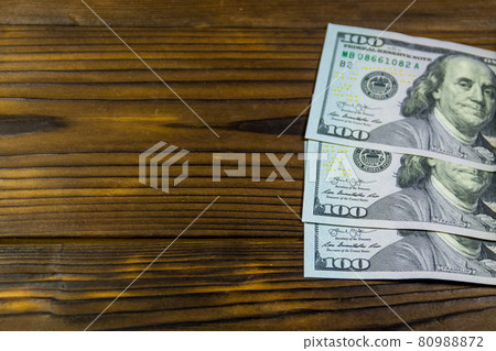 One hundred dollars bills on wooden desk One hundred dollars bills on wooden desk 80988872