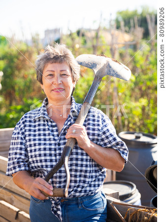Mature woman having horticultural instruments in garden on day 80989206