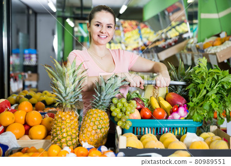 woman with basket with fresh greengrocery enjoying purchases in vegetable store 80989551