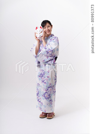 A woman in a yukata holding a fox face in her hand 80991373
