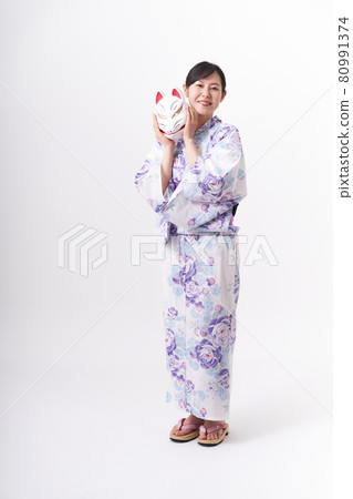 A woman in a yukata holding a fox face in her hand 80991374