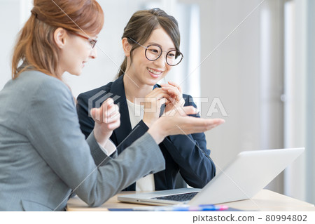 Two young Japanese and Western women with glasses talking while looking at a computer Photo cooperation: Japanese language school attached to Chuo College of Technology 80994802
