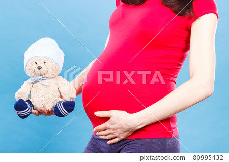 Pregnant woman holding fluffy teddy bear for kids, expecting for baby concept 80995432