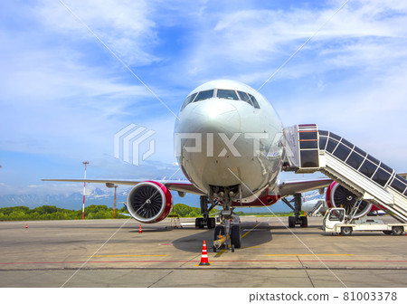 Airplane with a passenger boarding steps on the airport apron Airplane with a passenger boarding steps on the airport apron 81003378