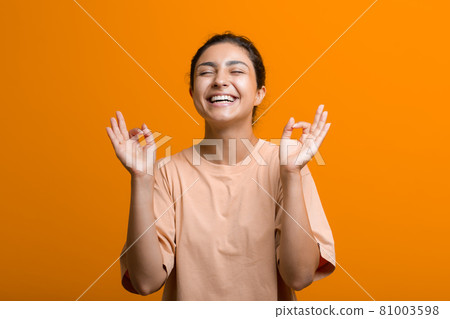 Portrait of young adult indian woman in sari meditating zen like with ok sign mudra gesture Portrait of young adult indian woman in sari meditating zen like with ok sign mudra gesture 81003598