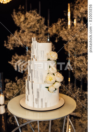 White-pink beautiful wedding cake on the background of the evening wedding arch White-pink beautiful wedding cake on the background of the evening wedding arch 81003856