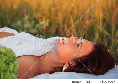 Charming woman in a field with a bouquet of hydrangea in a white men's shirt 81003997
