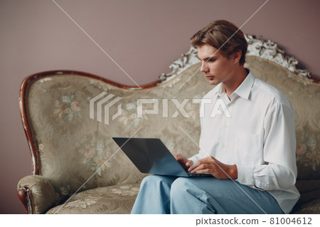 Portrait young man sitting with laptop at studio. Portrait young man sitting with laptop at studio. 81004612