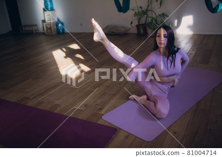 Woman doing aerial yoga in studio. Female practicing air yoga in hammock Woman doing aerial yoga in studio. Female practicing air yoga in hammock 81004714