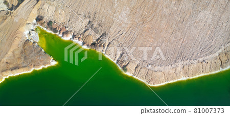Shore of toxic green lake in abandoned open pit copper mine. Aerial panorama from directly above Shore of toxic green lake in abandoned open pit copper mine. Aerial panorama from directly above 81007373