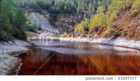 Shore of toxic red lake in open pit of old copper mine in a forest Shore of toxic red lake in open pit of old copper mine in a forest 81007377