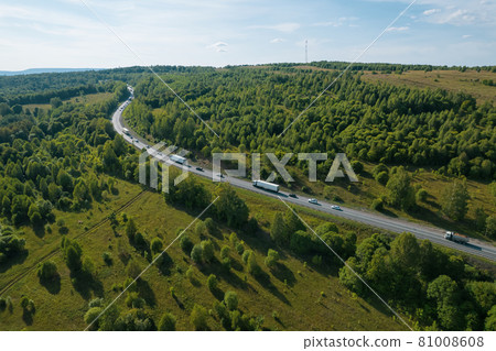 Aerial view of scenic road between green trees with pines on a sunny summer morning. Nature landscape in Siberia, Russia. A road passing through a coniferous forest, aerial shot from a drone. Aerial view of scenic road between green trees with pines on a sunny summer morning. Nature landscape in Siberia, Russia. A road passing through a coniferous forest, aerial shot from a drone. 81008608