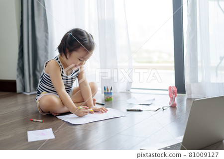 Asian little girl with a crayon drawing on the paper 81009127