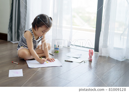 Asian little girl with a crayon drawing on the paper Asian little girl with a crayon drawing on the paper 81009128