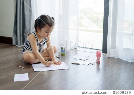 Asian little girl with a crayon drawing on the paper Asian little girl with a crayon drawing on the paper 81009129