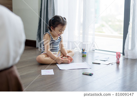 Asian little girl with a crayon drawing on the paper 81009147