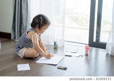 Asian little girl with a crayon drawing on the paper 81009151