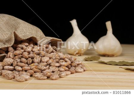 Dried Pinto Beans in Burlap Sac With Garlic and Bay Leaves in Background 81011866
