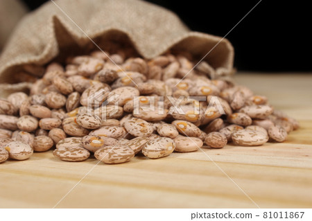 Burlap Bag of Dried Pinto Beans Spilled on Wooden Table Burlap Bag of Dried Pinto Beans Spilled on Wooden Table 81011867