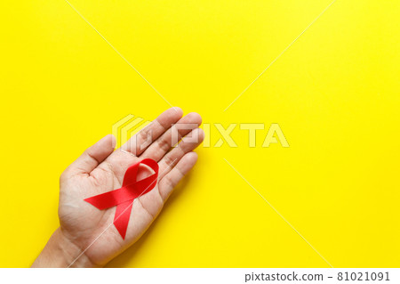 red AIDS awareness ribbon on yellow paper background. World aids day and healthcare and medicine concept red AIDS awareness ribbon on yellow paper background. World aids day and healthcare and medicine concept 81021091