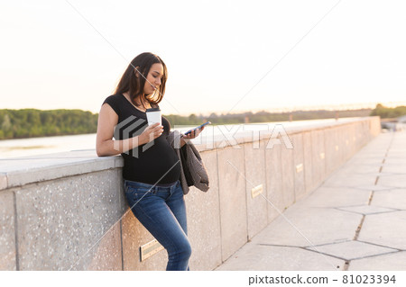 Pregnant woman with smartphone at park. Pregnancy, technology and communication concept. Space for text Pregnant woman with smartphone at park. Pregnancy, technology and communication concept. Space for text 81023394