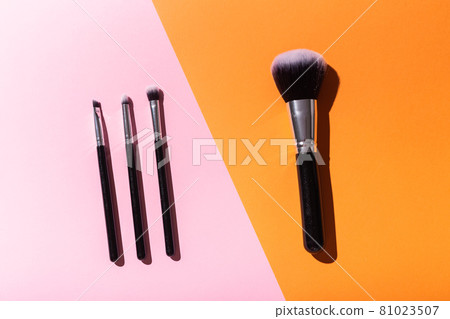 Various make-up brushes on pink and orange background, top view. Cosmetics and beauty concept. Various make-up brushes on pink and orange background, top view. Cosmetics and beauty concept. 81023507