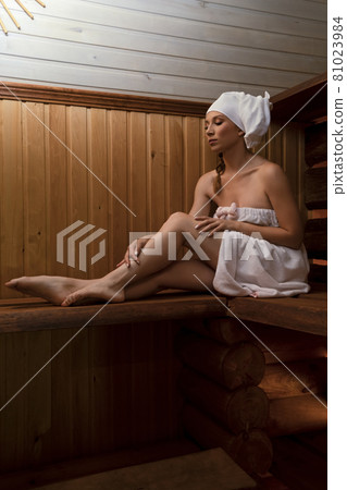 Relaxed woman in towel enjoying hot sauna 81023984