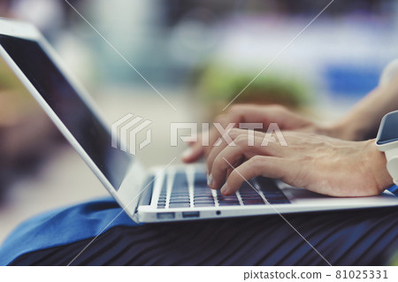 在戶外使用筆記本電腦的人手邊特寫綠色背景模糊 81025331