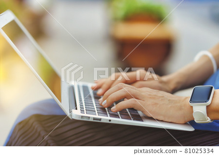 在戶外使用筆記本電腦的人手邊特寫綠色背景模糊 81025334