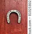 Old iron horseshoe on a wooden red painted door background. 81025802