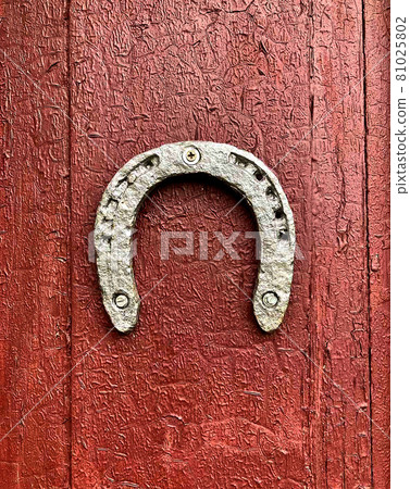 Old iron horseshoe on a wooden red painted door background. 81025802