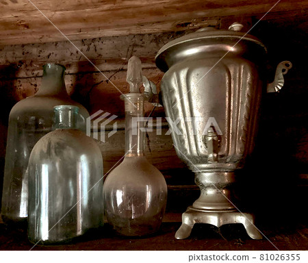 Vintage old antique dusty bottles decanter samovar, cobweb in an old abandoned house, on a wooden background. 81026355