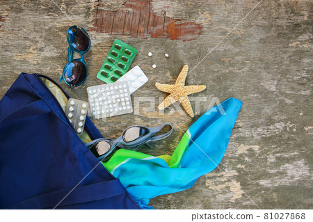 Summer women's beach accessories for your sea holiday and pill on old wooden background.  81027868