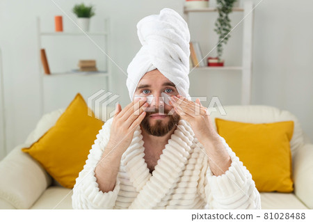 Bearded man sitting with eye patches on his face. Wrinkles and face home care for men. Bearded man sitting with eye patches on his face. Wrinkles and face home care for men. 81028488