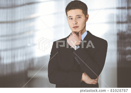 Young businessman wearing suit and tie, while standing in the office. Business success concept nowadays 81028787