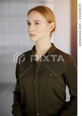 Friendly adult casual dressed business woman standing straight in sunny office. Business headshot 81028834