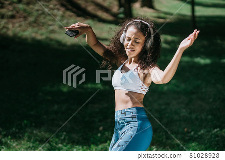 beautiful athletic woman in headphones dancing outdoors . beautiful athletic woman in headphones dancing outdoors . 81028928