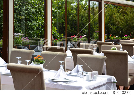 Ornate empty dining tables in a modern restaurant ready to serve 81030224