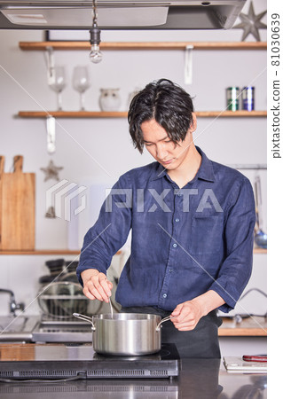 Image of a young man cooking in an apron cooking in the kitchen Image of a young man cooking in an apron cooking in the kitchen 81030639