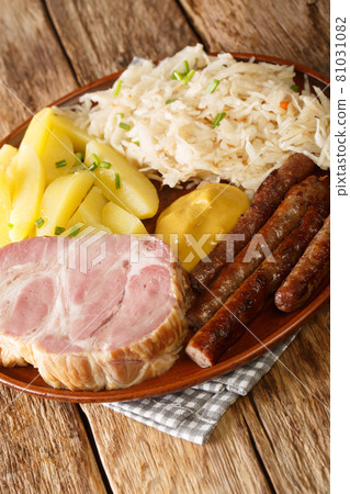 Kassler and sausages served with sauerkraut and boiled potatoes closeup in the plate. Vertical Kassler and sausages served with sauerkraut and boiled potatoes closeup in the plate. Vertical 81031082