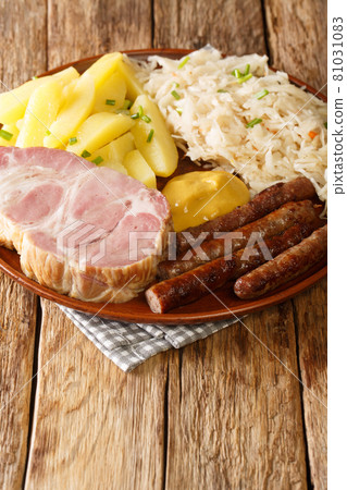 smoked Kassler pork neck and fried sausages with Sauerkraut mashed potatoes and mustard on wooden table closeup in the plate. Vertical 81031083