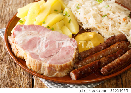 Sausage, Kassler pork neck, boiled potatoes, sauerkraut and mustard is an traditional German winter dish on wooden table closeup. Horizontal Sausage, Kassler pork neck, boiled potatoes, sauerkraut and mustard is an traditional German winter dish on wooden table closeup. Horizontal 81031085