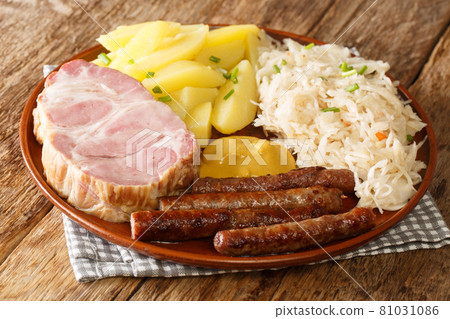 Smoked pork neck and sausages with cabbage Sauerkraut boiled potatoes and mustard closeup in the plate. Horizontal Smoked pork neck and sausages with cabbage Sauerkraut boiled potatoes and mustard closeup in the plate. Horizontal 81031086