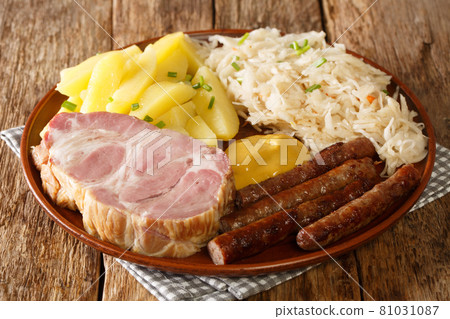 Traditional German food smoked sausage, Kassler pork neck, sauerkraut, mustard and boiled potatoes closeup in the plate. Horizontal Traditional German food smoked sausage, Kassler pork neck, sauerkraut, mustard and boiled potatoes closeup in the plate. Horizontal 81031087
