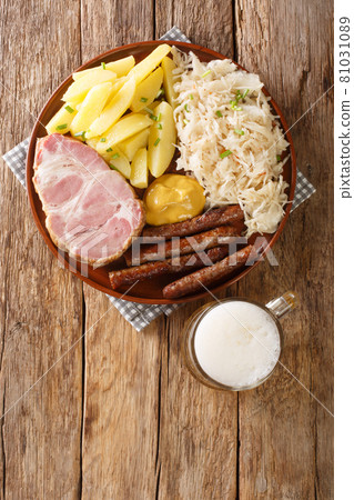 smoked Kassler pork neck and fried sausages with Sauerkraut mashed potatoes and mustard on wooden table. Vertical top view smoked Kassler pork neck and fried sausages with Sauerkraut mashed potatoes and mustard on wooden table. Vertical top view 81031089