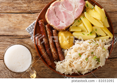 German Kassler pork neck with Sauerkraut potatoes and mustard on wooden table closeup. Horizontal top view German Kassler pork neck with Sauerkraut potatoes and mustard on wooden table closeup. Horizontal top view 81031091
