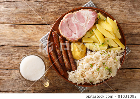 Sausage, Kassler pork neck, boiled potatoes, sauerkraut and mustard is an traditional German winter dish on wooden table closeup. Horizontal top view Sausage, Kassler pork neck, boiled potatoes, sauerkraut and mustard is an traditional German winter dish on wooden table closeup. Horizontal top view 81031092