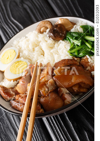 Stewed pork leg with rice, eggs and herb Thai Khao Kha Moo closeup in the bowl. Vertical Stewed pork leg with rice, eggs and herb Thai Khao Kha Moo closeup in the bowl. Vertical 81031093