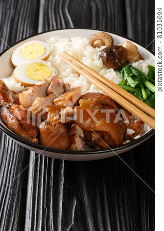 Chinese Thai food Khao Kha Moo Jasmine rice with stewed pork leg boiled eggs, mushrooms closeup in the bowl. Vertical Chinese Thai food Khao Kha Moo Jasmine rice with stewed pork leg boiled eggs, mushrooms closeup in the bowl. Vertical 81031094