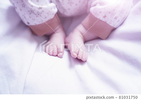 the baby's legs are lying on a white bed 81031750